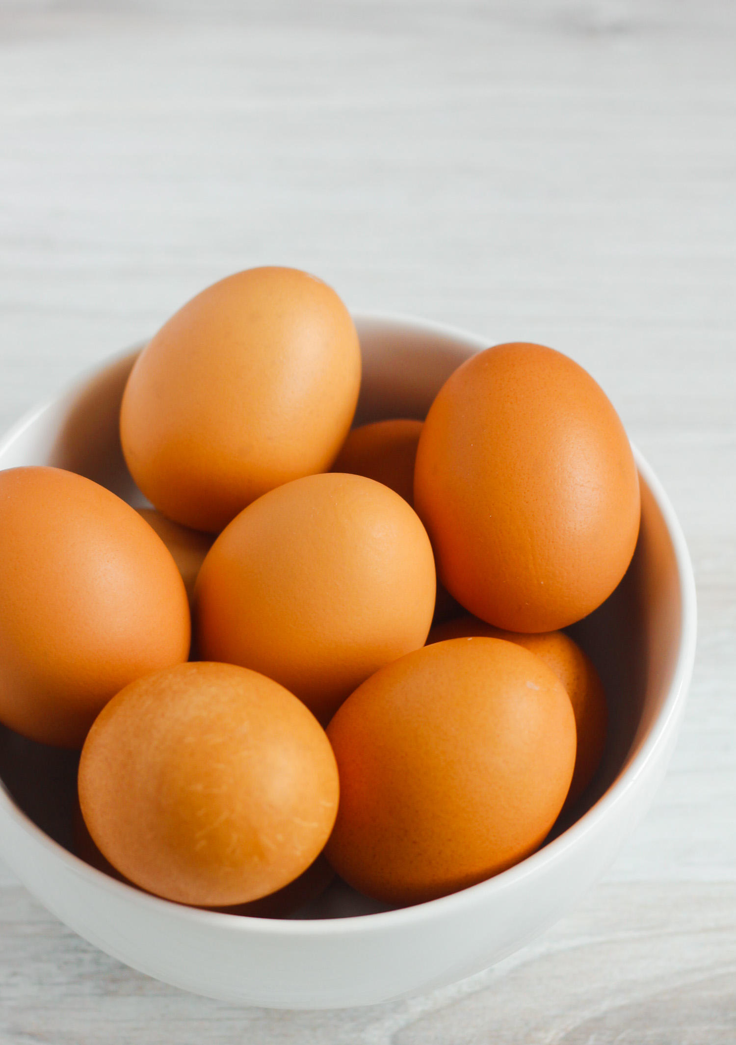 side view of brown eggs in white bowl