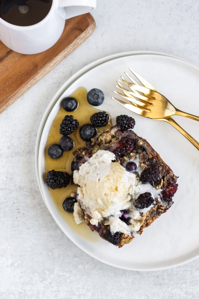 piece of baked berry oatmeal with coconut whipped cream and syrup on top