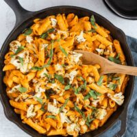 overhead view of roasted red pepper pasta sprinkled with basil in cast iron skillet