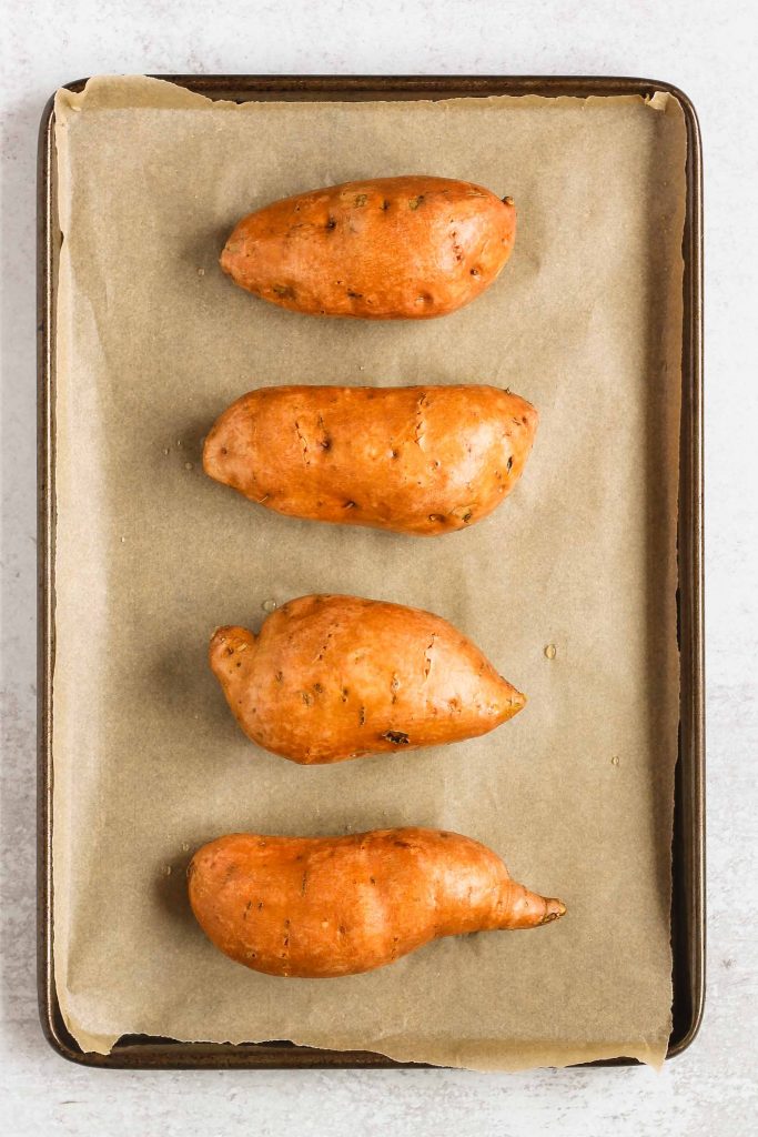 overhead view of raw sweet potatoes on baking sheet