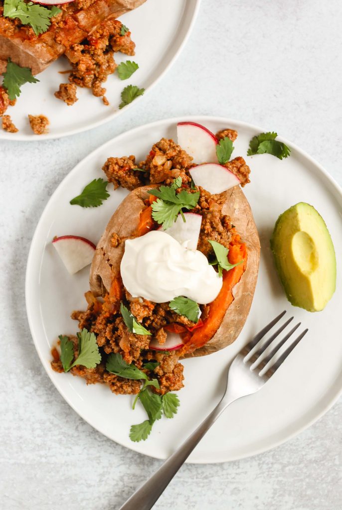 overhead view of stuffed sweet potato topped with cilantro and sour cream