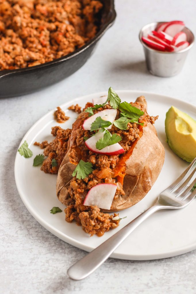 side view of chili stuffed sweet potato on white plate