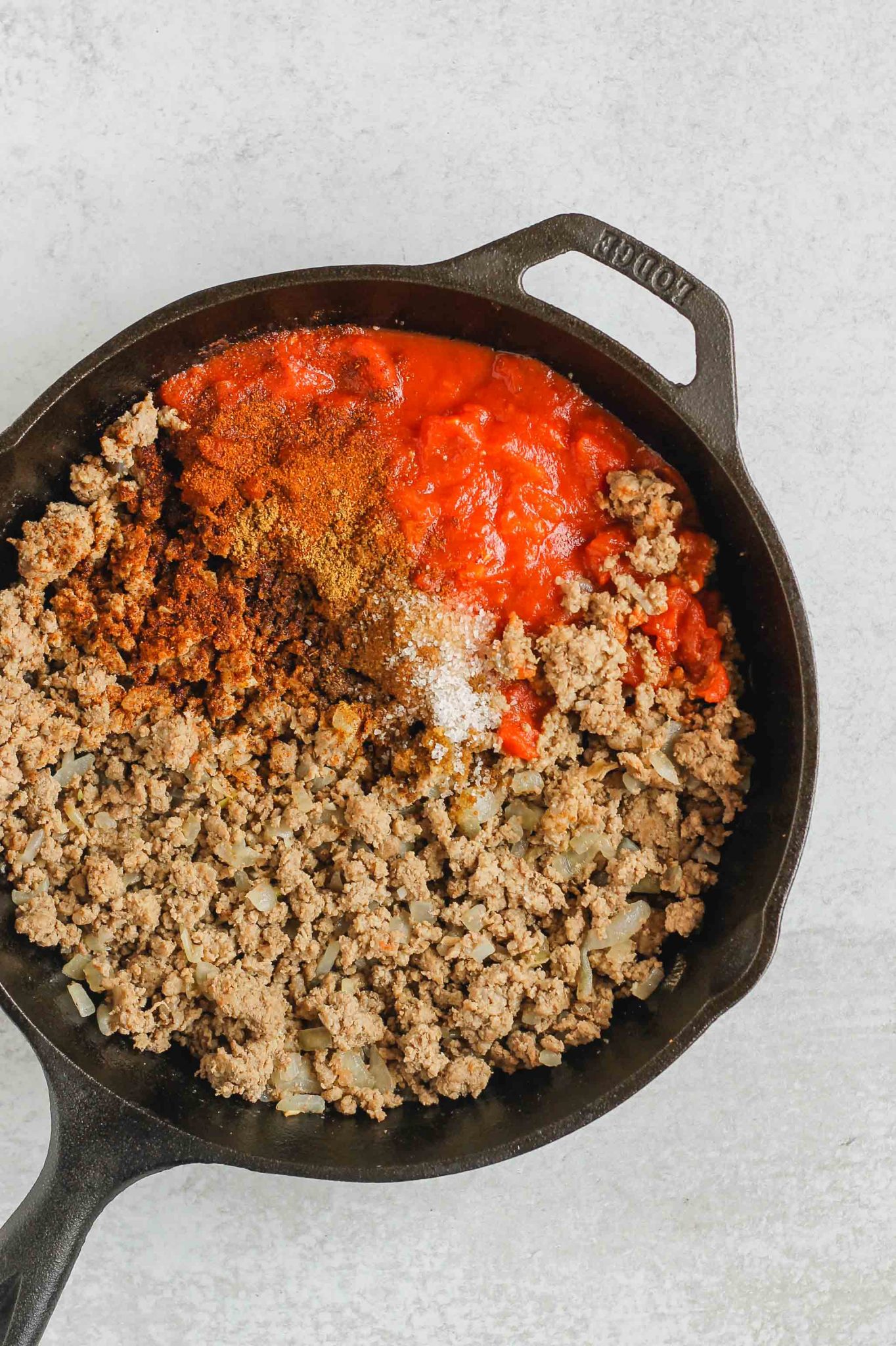  cooked ground beef, seasoning, and tomatoes in cast iron skillet before being mixed together