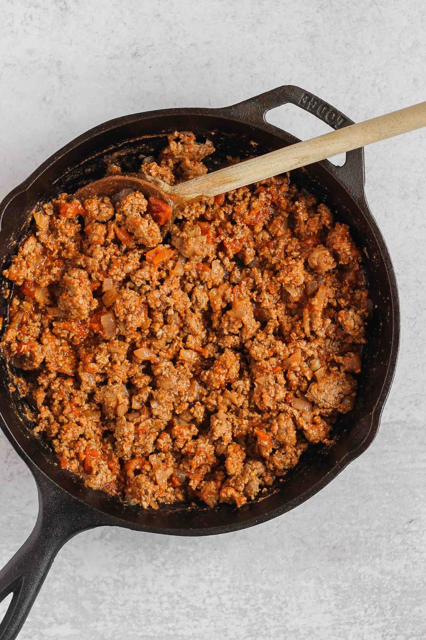 cooked ground beef and canned tomatoes mixed together in a cast iron skillet