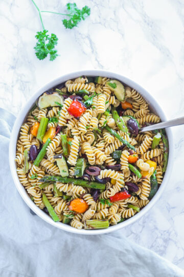 overhead view of grilled vegetable pasta salad in large round serving bowl with spoon