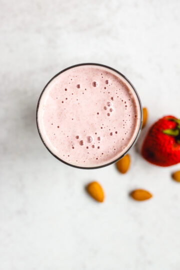 overhead view of strawberry almond smoothie in a glass