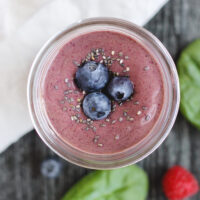 overhead view of berry smoothie topped with blueberries and chia seeds in a glass mason jar