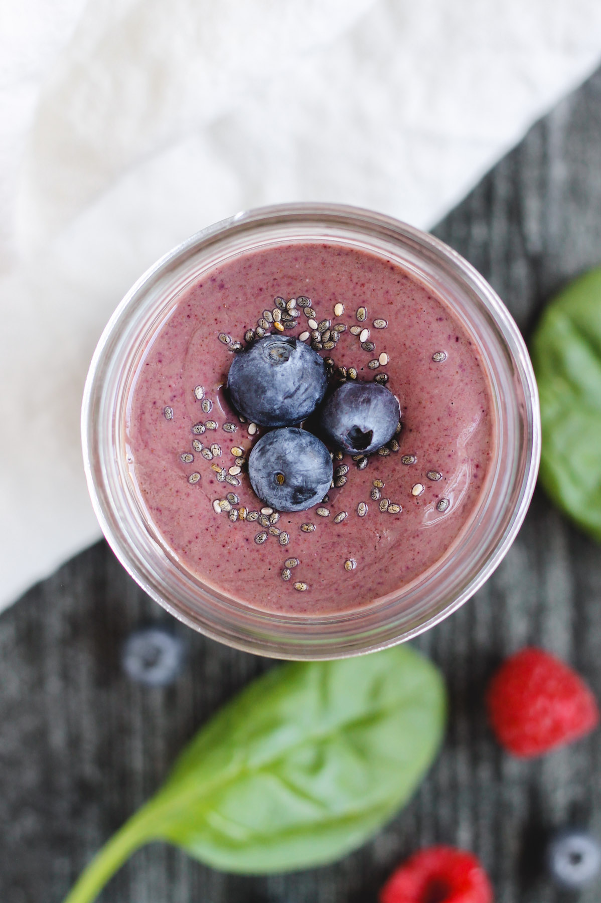 overhead view of berry smoothie topped with blueberries and chia seeds in a glass mason jar