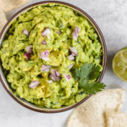 overhead view of guacamole in a serving bowl with chips sprinkled on the side