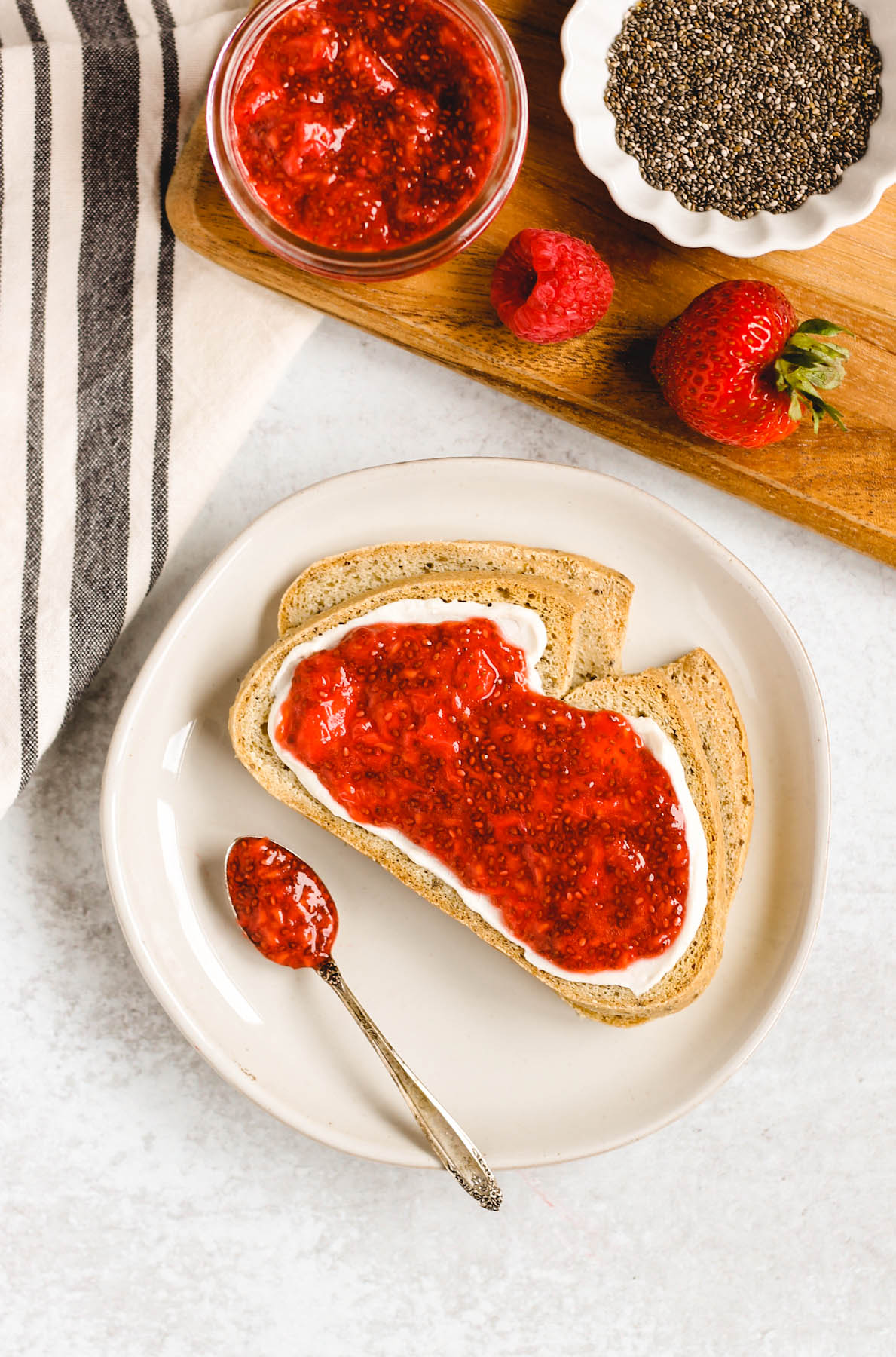 two slices of toast on a plate with cream cheese and berry chia jam spread on toast