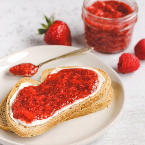 side view of two slices of toast, stacked on top of each other; top toast with cream cheese and jam spread on it