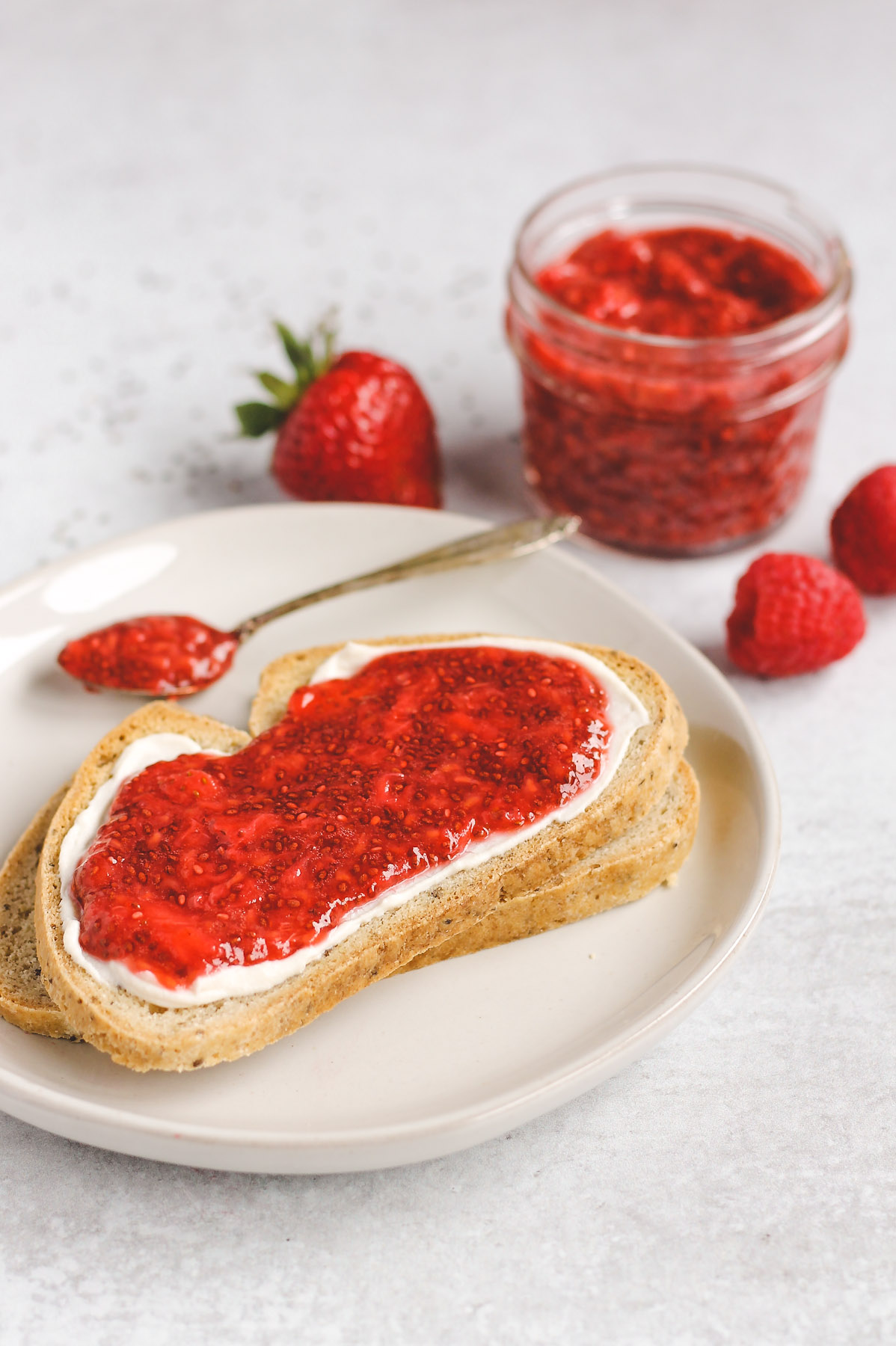 two slices of toast, stacked on top of each other; top toast with cream cheese and jam spread on it