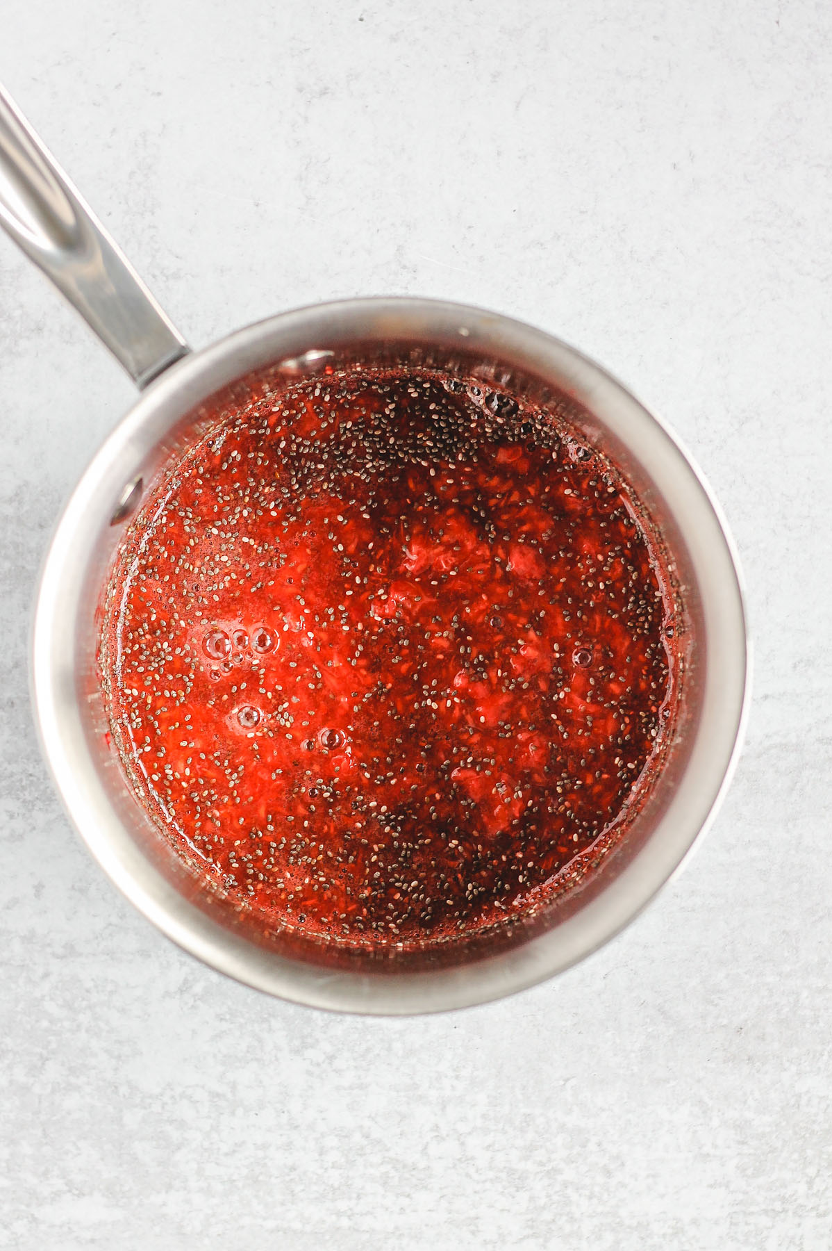 sauce pan with mashed strawberries, raspberries, and chia seeds