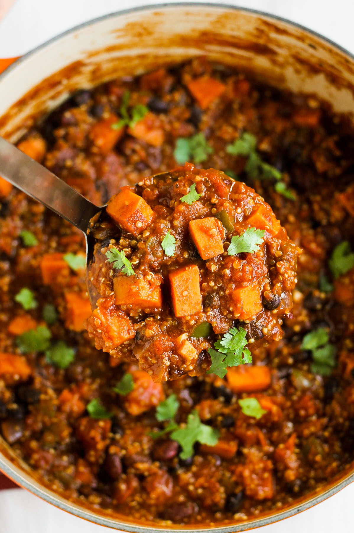 sweet potato chili in a large pot with a big soup ladle scooping some chili out.