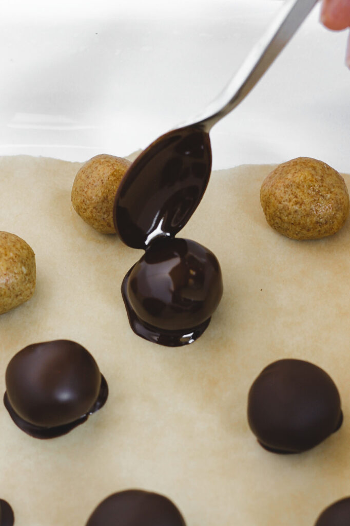chocolate covered peanut butter ball being placed on parchment paper