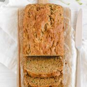 loaf of zucchini bread half sliced on a cutting board