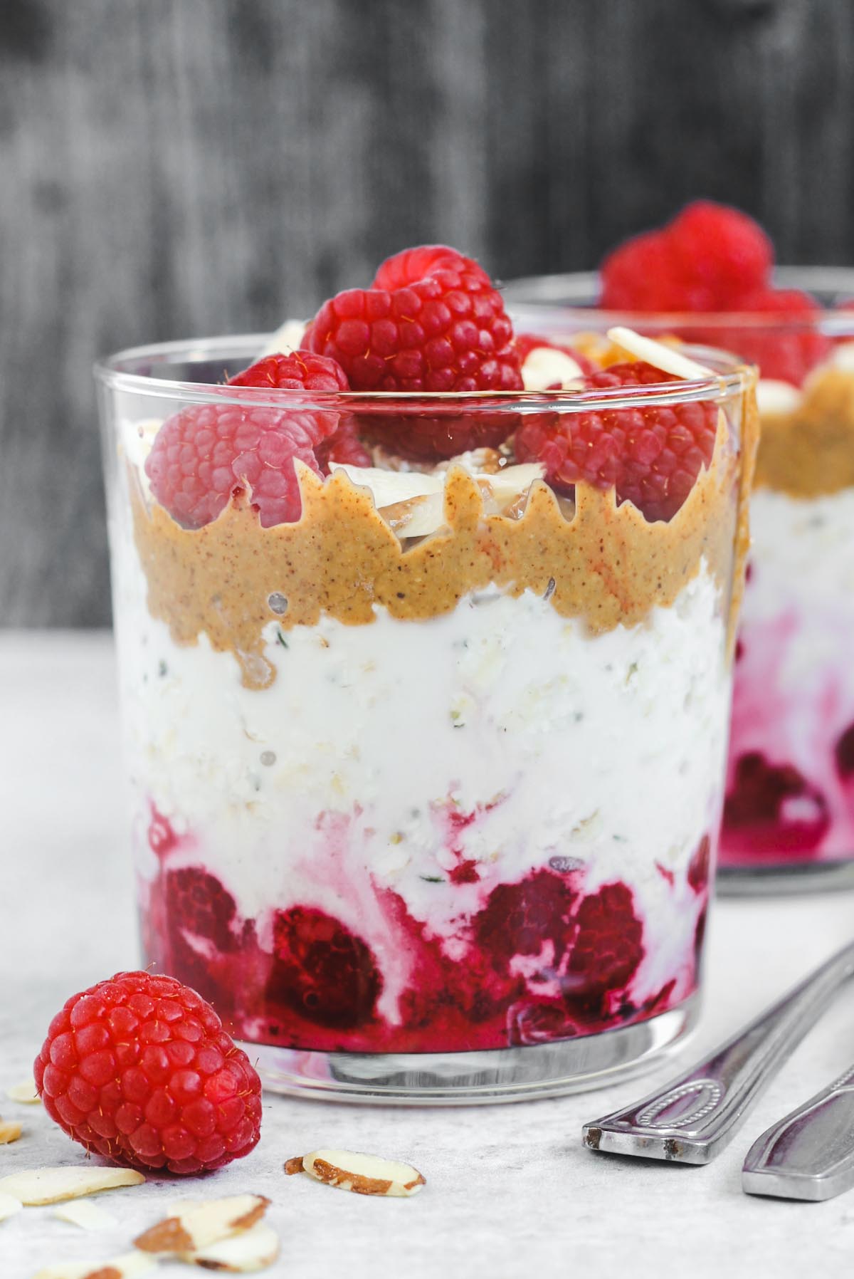 glass filled with layers of raspberries, overnight oats, and almond butter