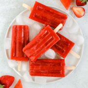 strawberry watermelon popsicles on a round white plate with ice cubes