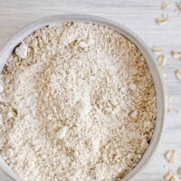 Oat flour in ceramic bowl with text overlay for Pinterest