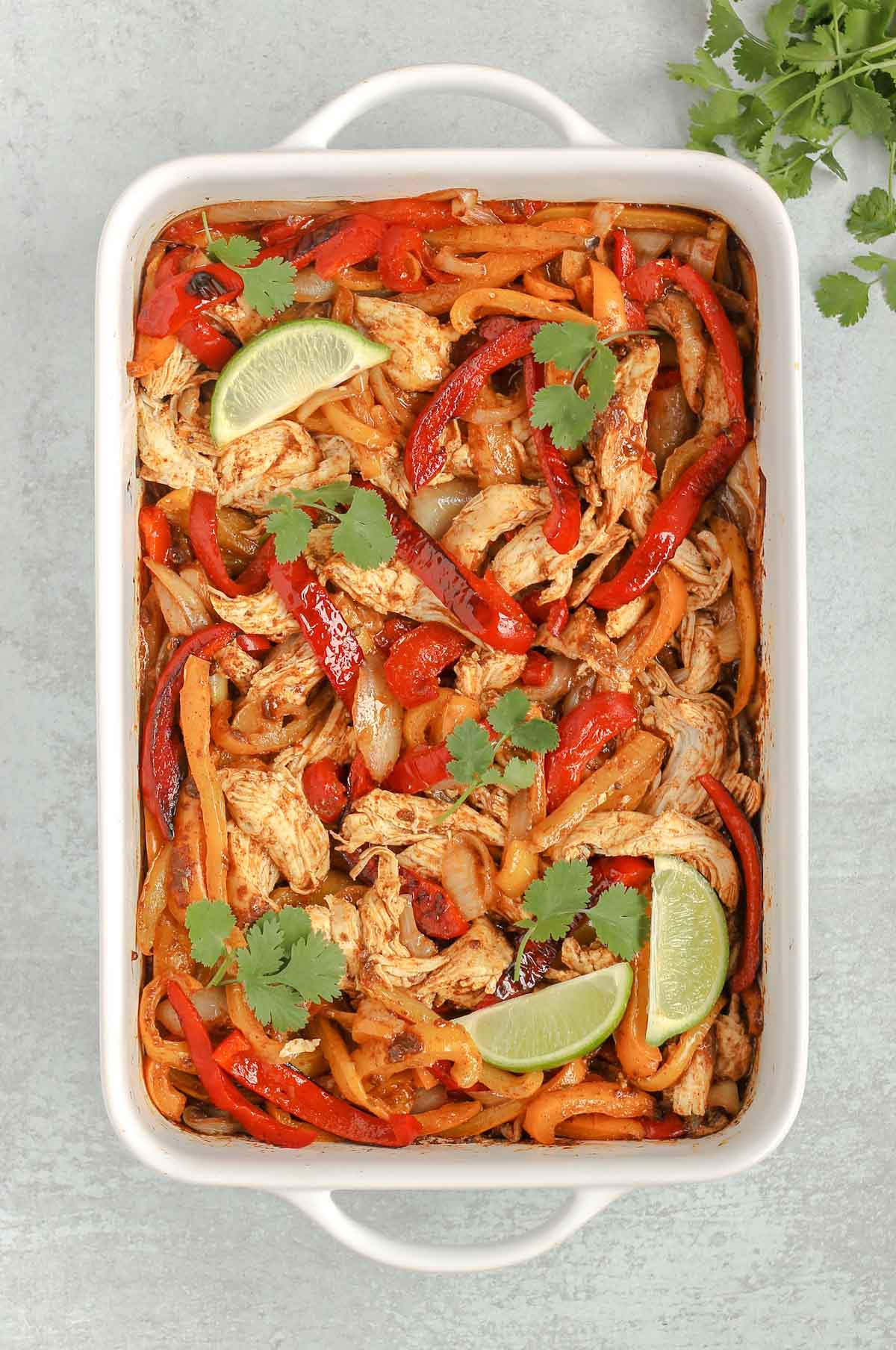 cooked shredded chicken and cooked peppers and onions all mixed together in a white baking dish