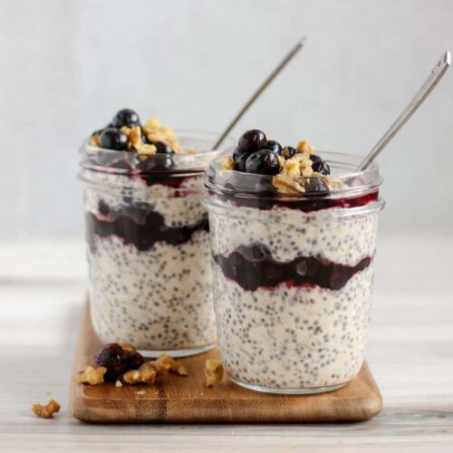 two mason jars filled with overnight oats with chia seeds and blueberries