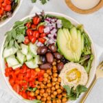 Mediterranean salad in shallow salad bowl with side of tahini dressing.