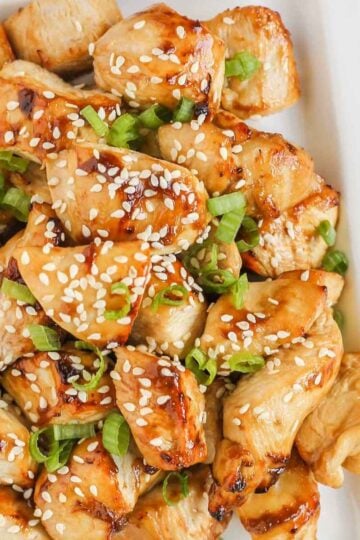 Pieces of air fried teriyaki chicken on a white plate.
