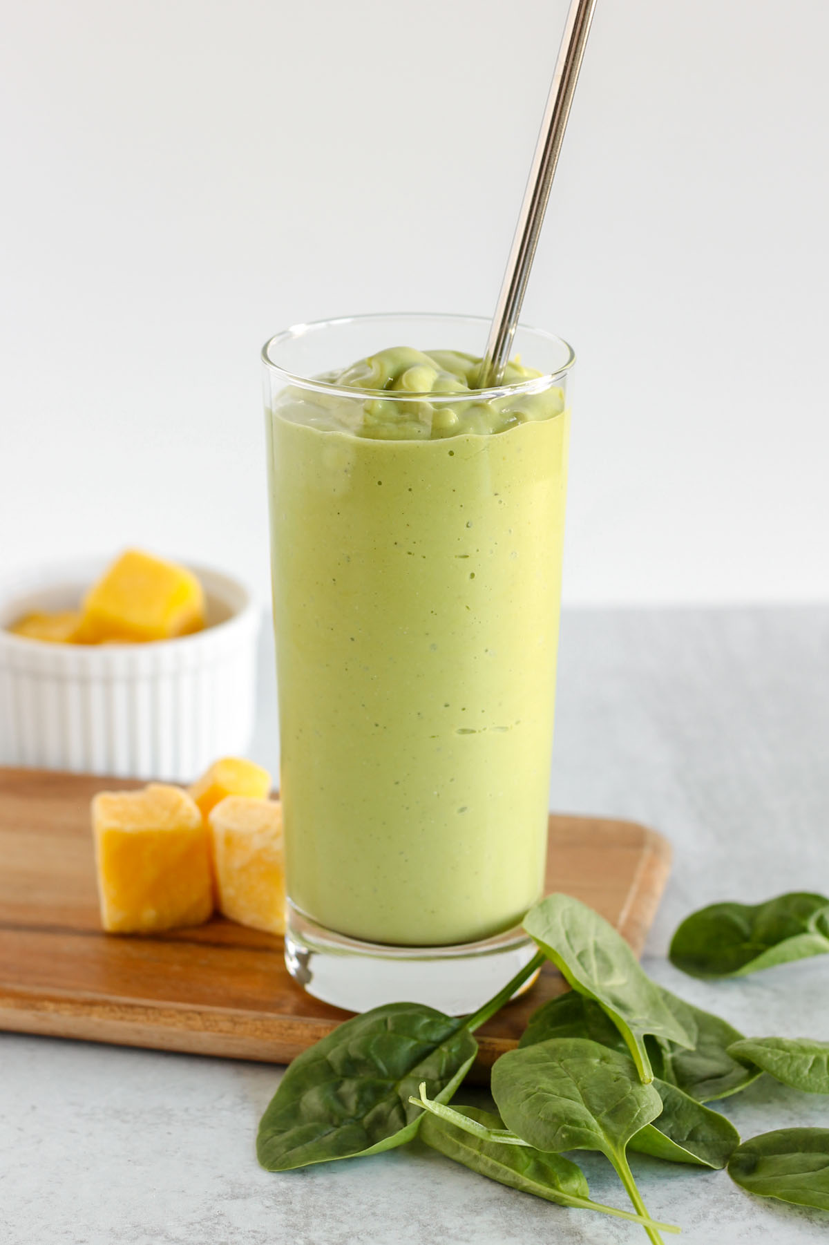 Tall glass filled with spinach mango smoothie.