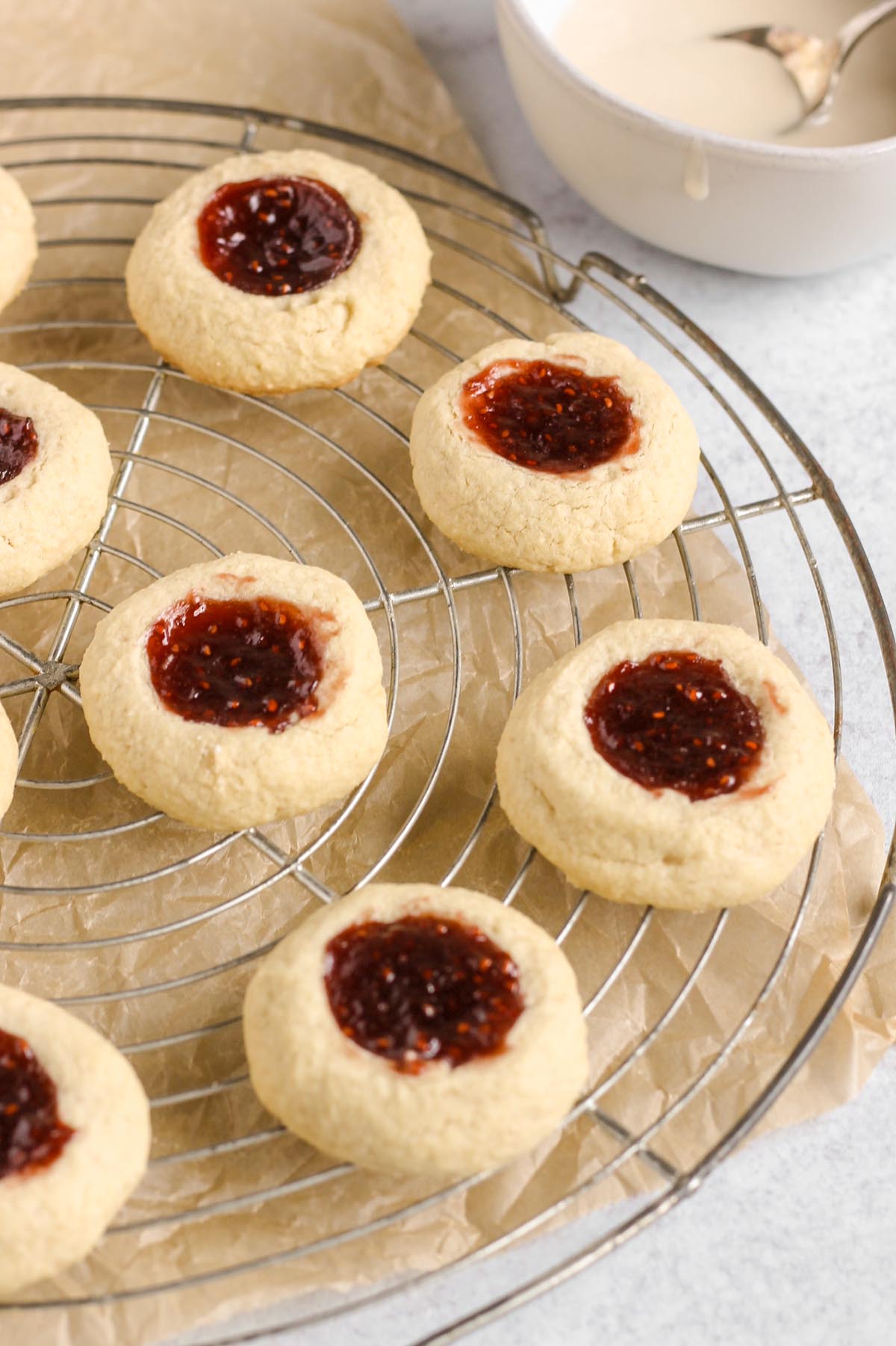 Baked thumbprint cookies on a wire cooling rack.