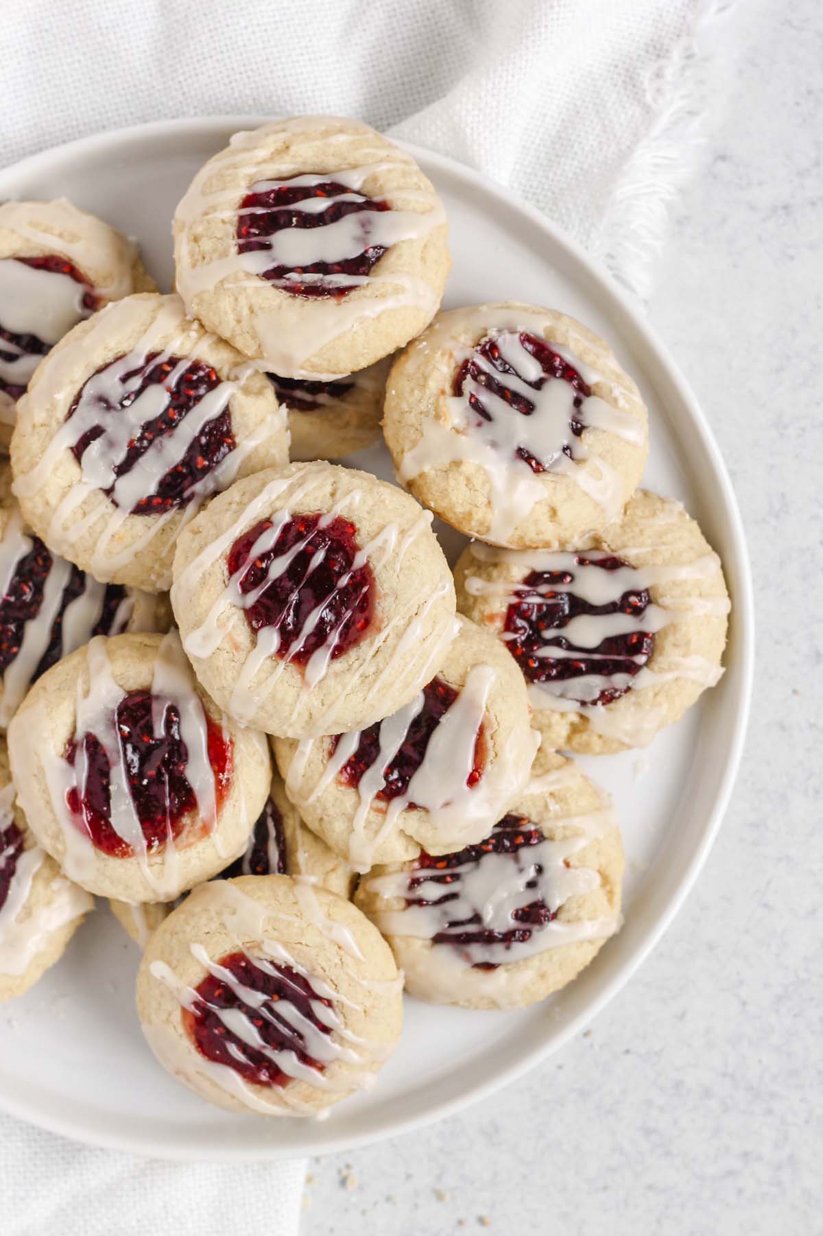 Overhead view of gluten-free raspberry thumbprint cookies on a white plate.