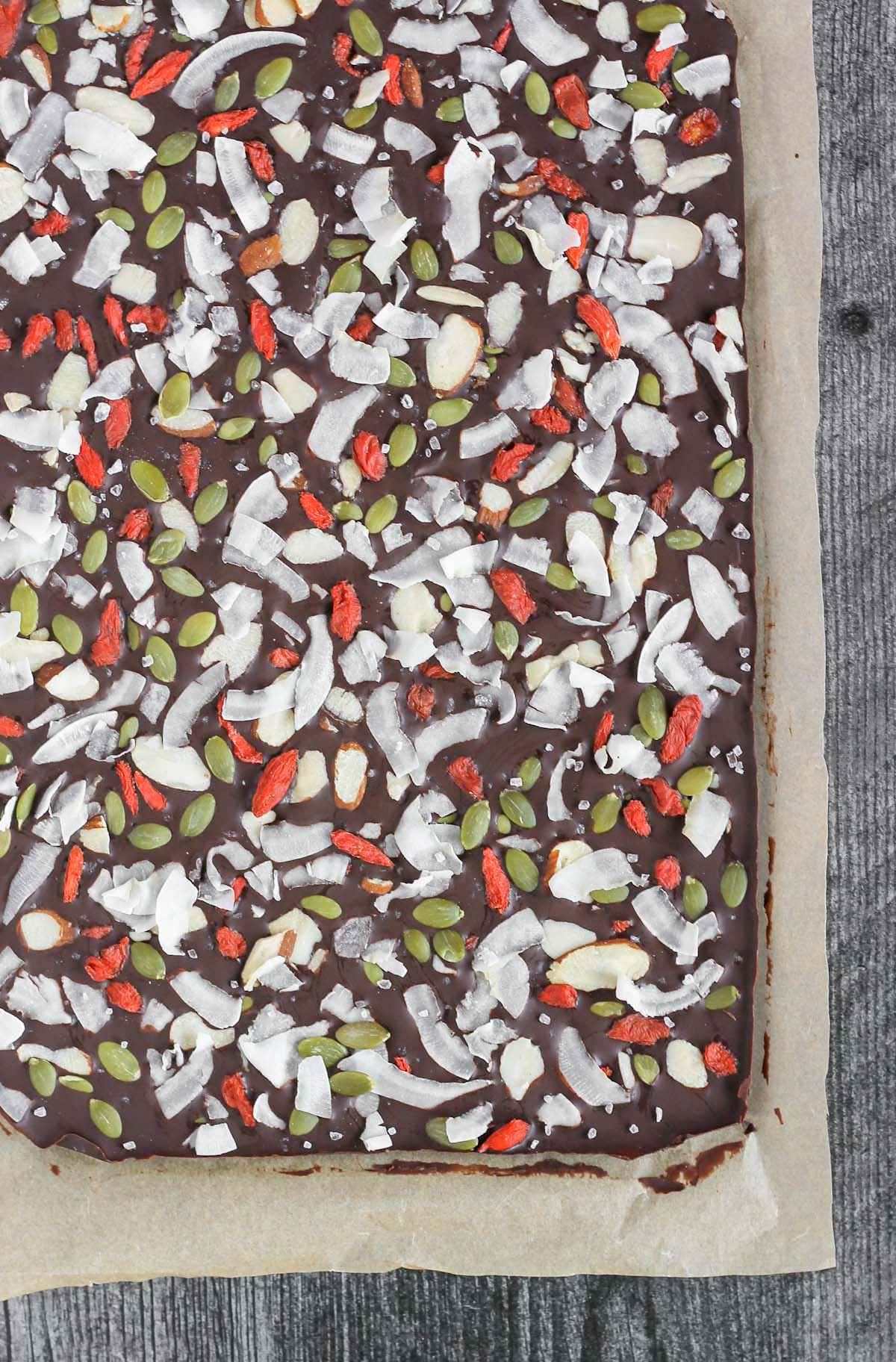 Large sheet of solid chocolate bark with dried fruit, nuts, and seeds.