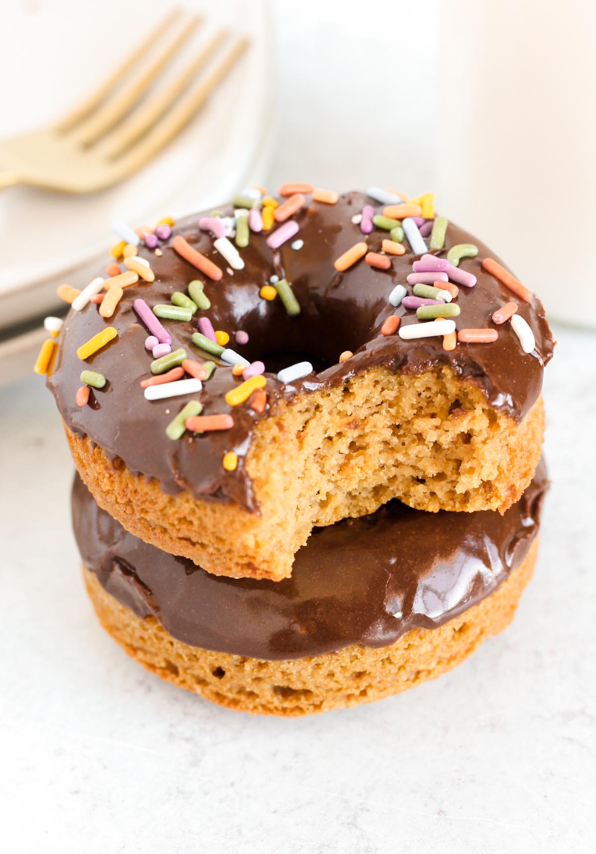 Chocolate covered donut with sprinkles with a bit taken out of it.