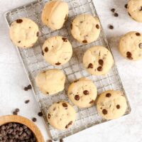 Mini chocolate chip muffins spread out on a wire cooling rack.