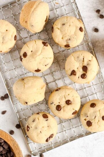 Mini chocolate chip muffins spread out on a wire cooling rack.