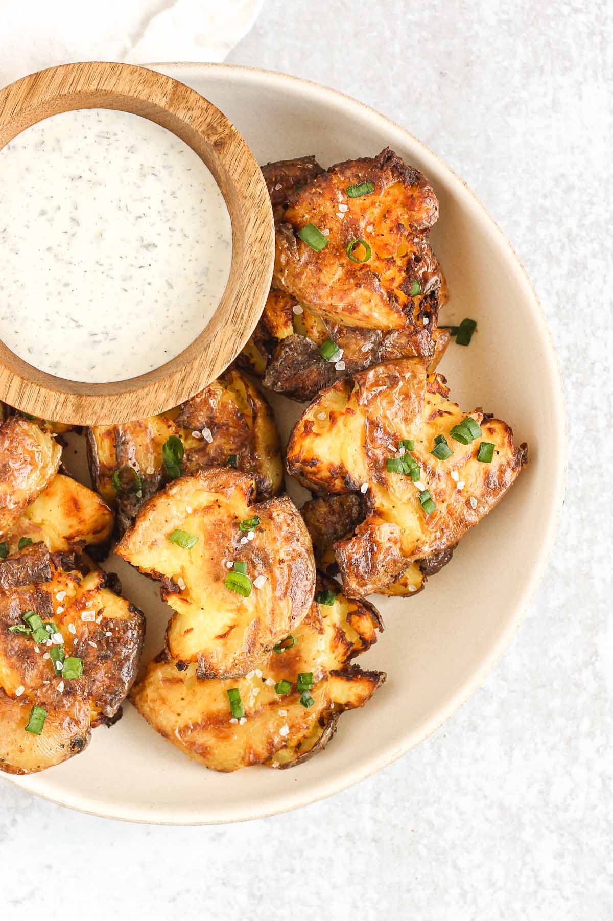 Fried smashed potatoes on a plate with a side of ranch.