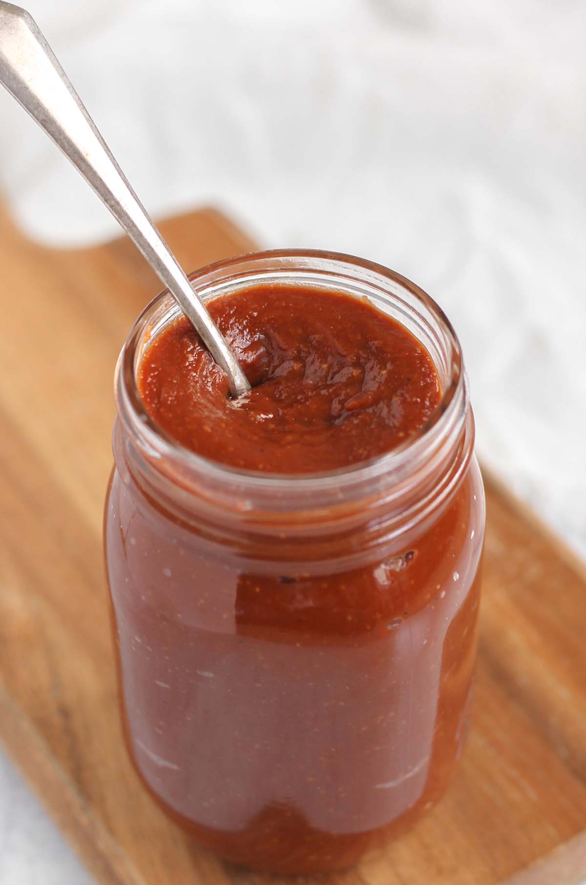 Whole 30 BBQ sauce in a mason jar with a spoon dipped in the sauce.