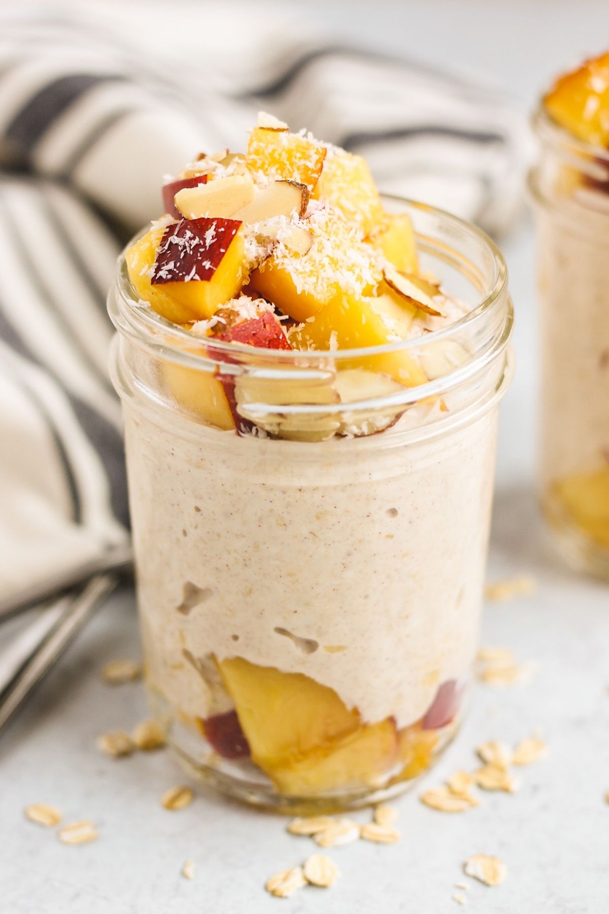 Mason jar filled with overnight oats topped with peaches and almond slices.