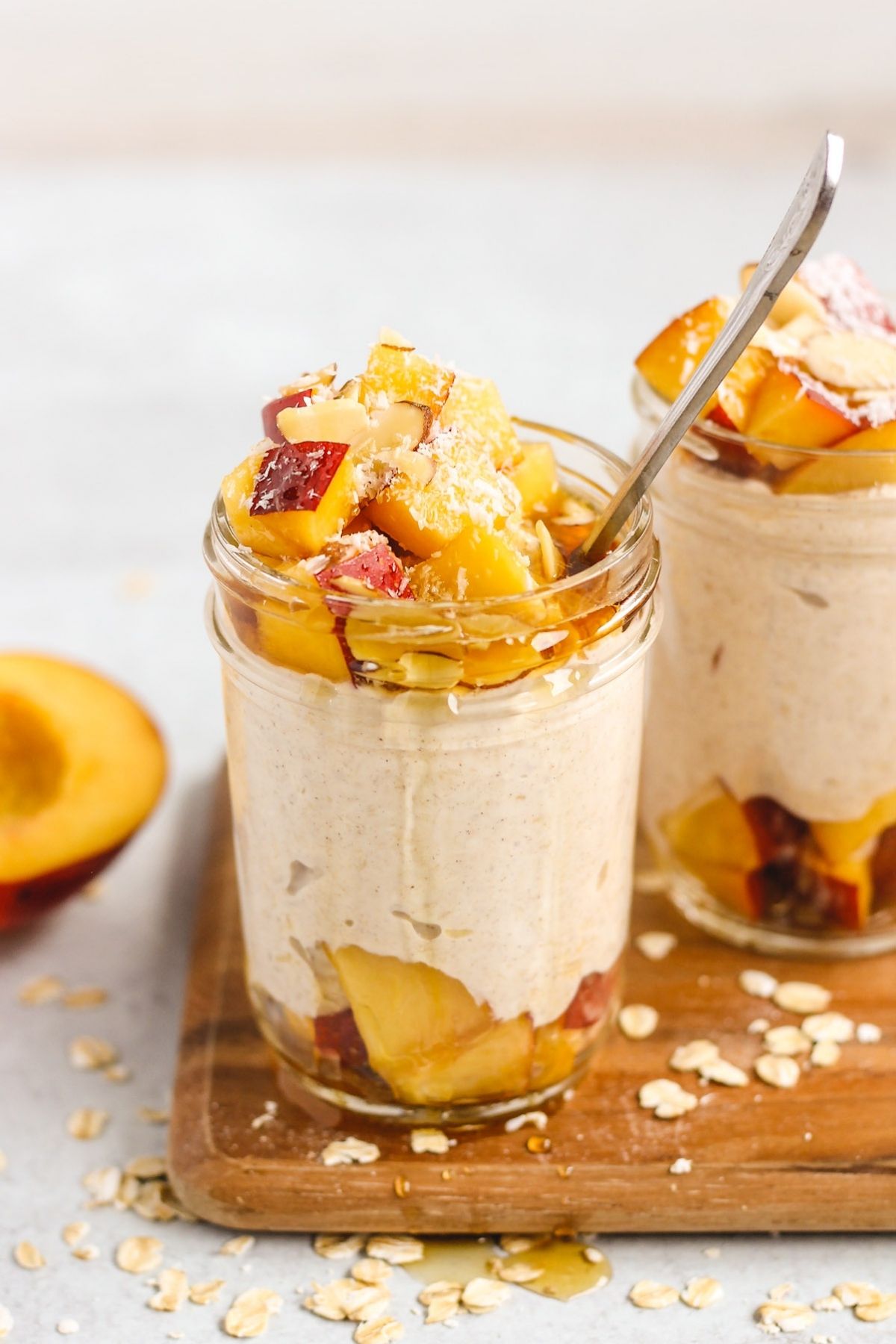 Peaches and cream overnight oats dripping with syrup in a mason jar with a spoon.