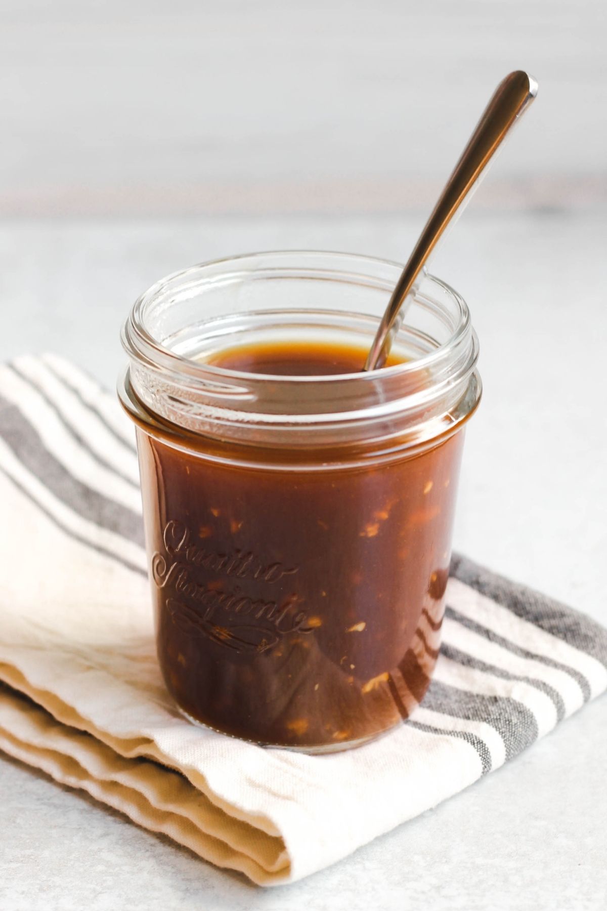 A spoon in a mason jar filled with teriyaki sauce.