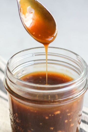Teriyaki sauce dripping from a spoon over a mason jar filled with teriyaki.