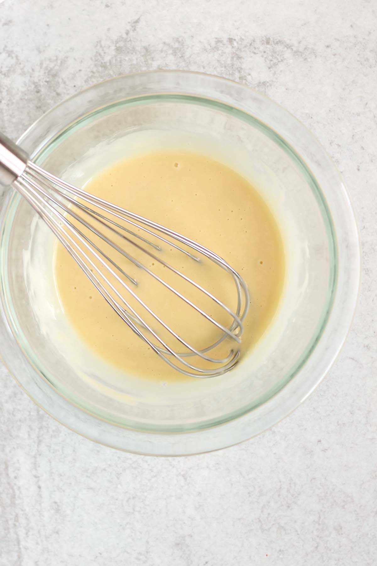 Coleslaw dressing being whisked in a mixing bowl.