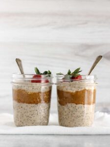 Two mason jars filled with overnight oats and almond butter topped with a strawberry.