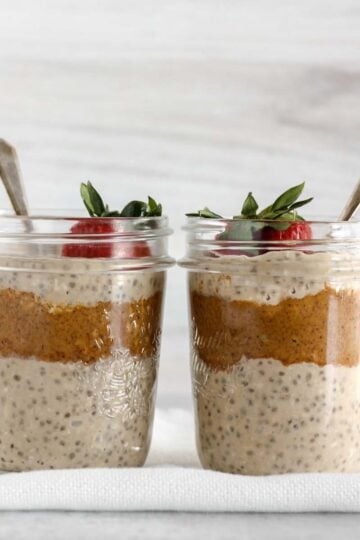 Two mason jars filled with overnight oats and almond butter topped with a strawberry.