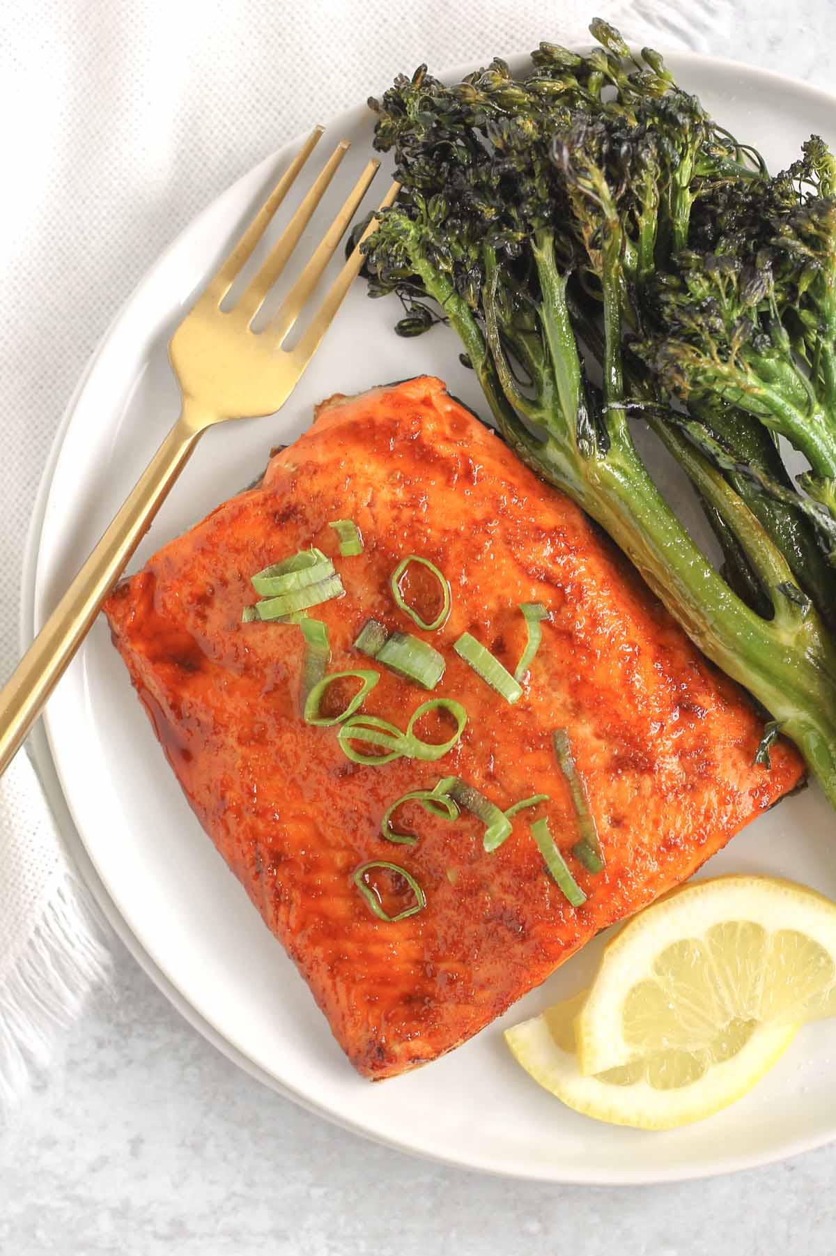 Salmon fillet topped with sliced green onions on a white plate.