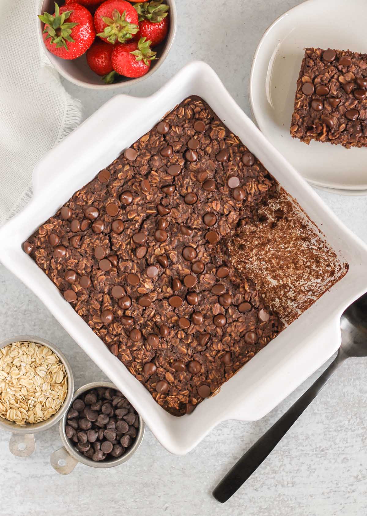 chocolate baked oats in a baking dish with a square piece cut out of the oats.