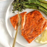 A gold fork cutting into a salmon fillet.