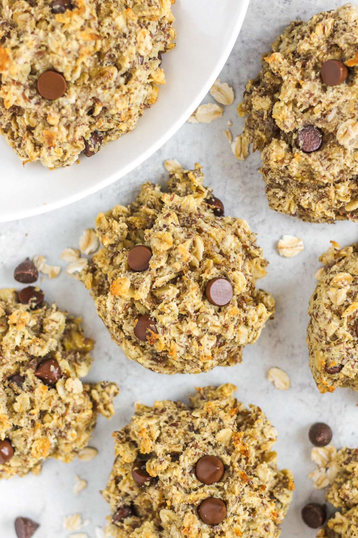 Oatmeal breakfast cookies with chocolate chips laid out on a gray surface.