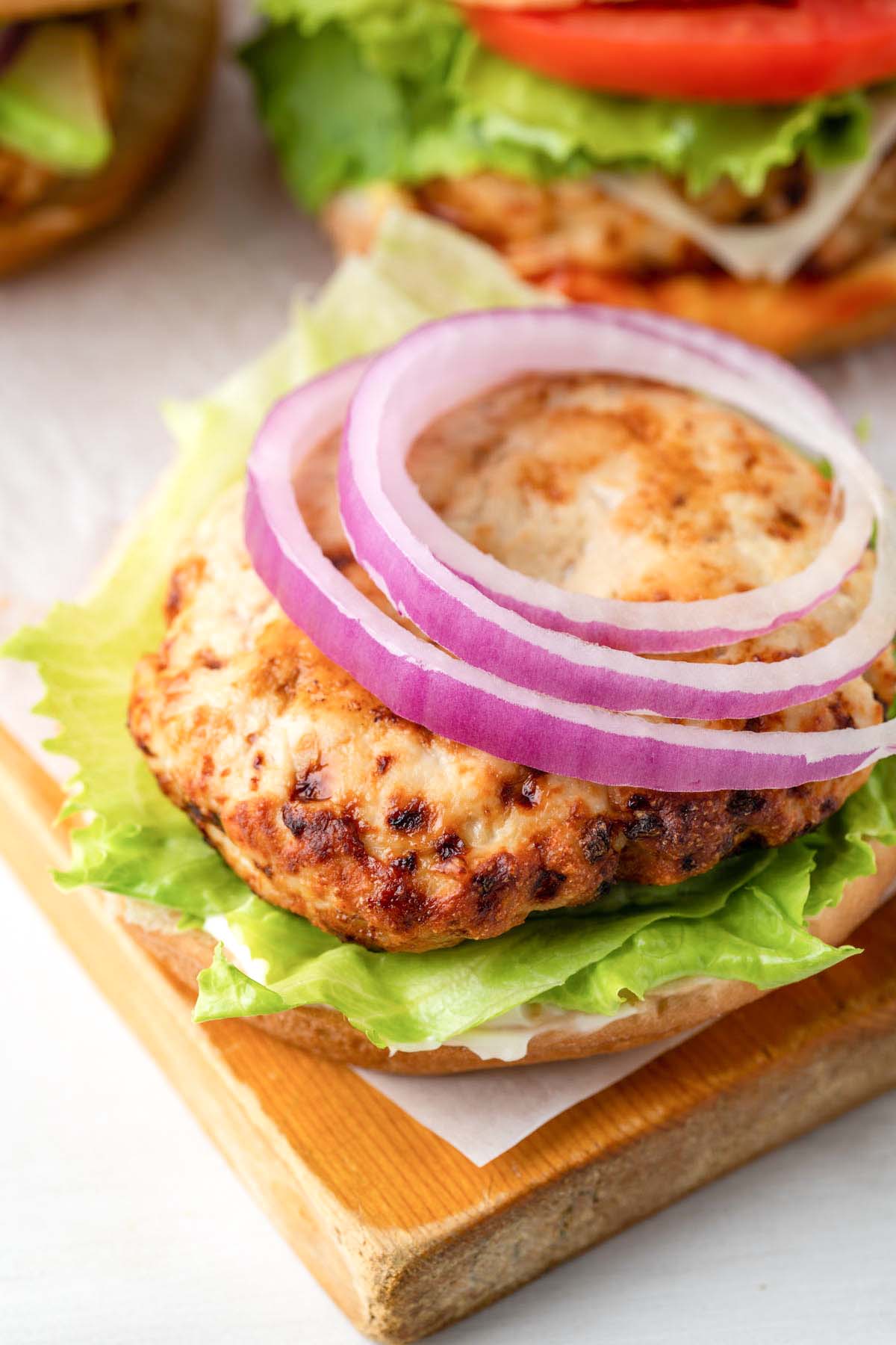 Turkey burger patty on a bottom bun with lettuce and onion.