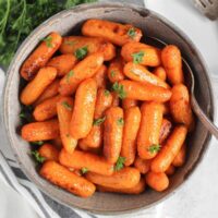 Air fried roasted baby carrots in a gray serving bowl with a serving spoon.
