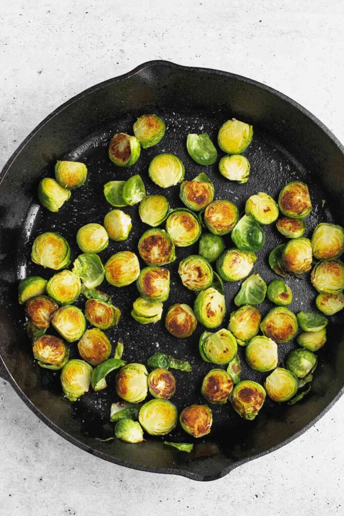 Sliced and roasted Brussels sprouts in a cast iron skillet.